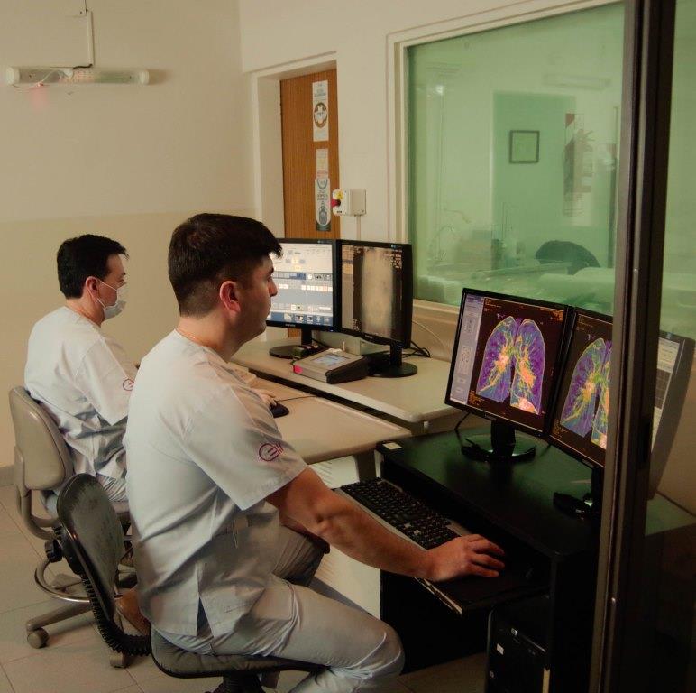 Dos técnicos radiólogos, cada uno realizando trabajo de imagenología en sistema de computadora