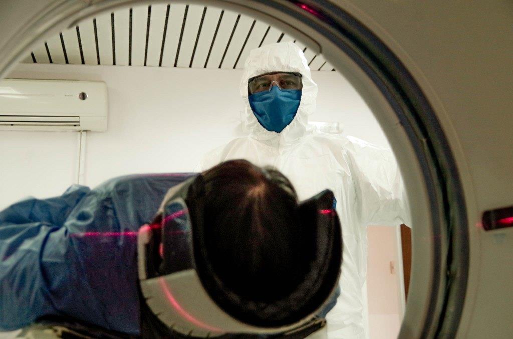 Paciente de sexo femenino recostada en tomógrafo en funcionamiento, acercamiento en la zona de la cabeza